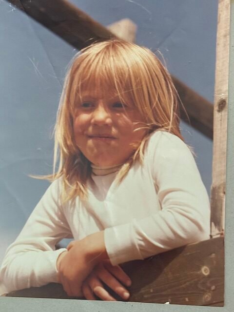 Picture of the Founder at age of five years old
standing up in the play tower on picture day wearing the white sweather